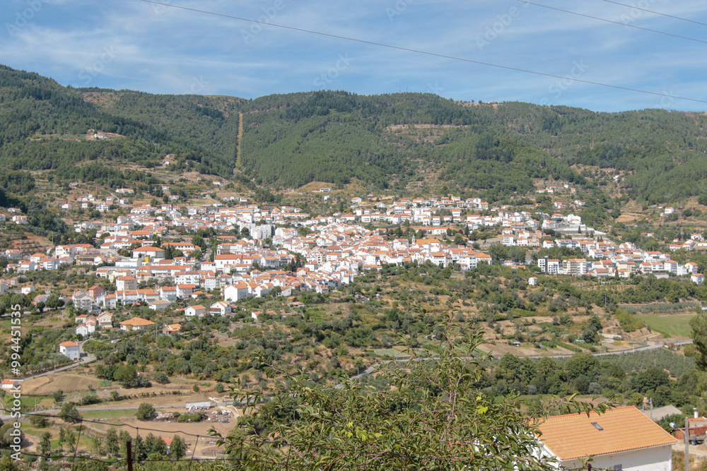 Obraz premium Vista panorâmica da Serra da Estrela, com seus imponentes picos rochosos, vastos campos verdes e céu claro, oferecendo uma paisagem tranquila e natural da maior montanha de Portugal.