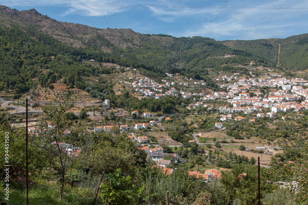 Fototapeta premium Vista panorâmica da Serra da Estrela, com seus imponentes picos rochosos, vastos campos verdes e céu claro, oferecendo uma paisagem tranquila e natural da maior montanha de Portugal.