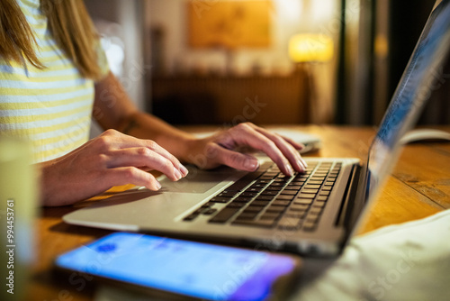 Woman late night working on laptop and smartphone at home