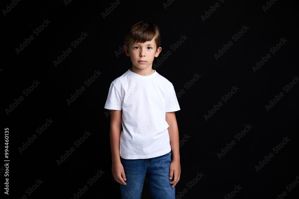Sad boy child, wearing white t-shirt over black background. Sad boy child, wearing white t-shirt over black background.