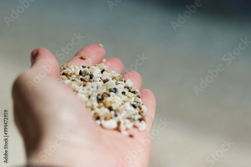 hand holding coarse sand particles close up. Black white sand particles