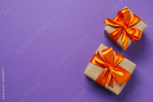 Top view photo of giftboxes with orange satin ribbon bow on color background 