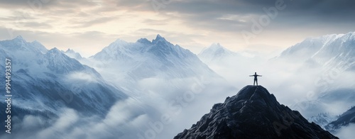 Person standing triumphantly on a mountain peak overlooking misty valleys at ...