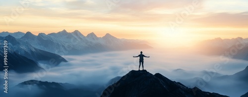 Person standing triumphantly on a mountain peak overlooking misty valleys at ...