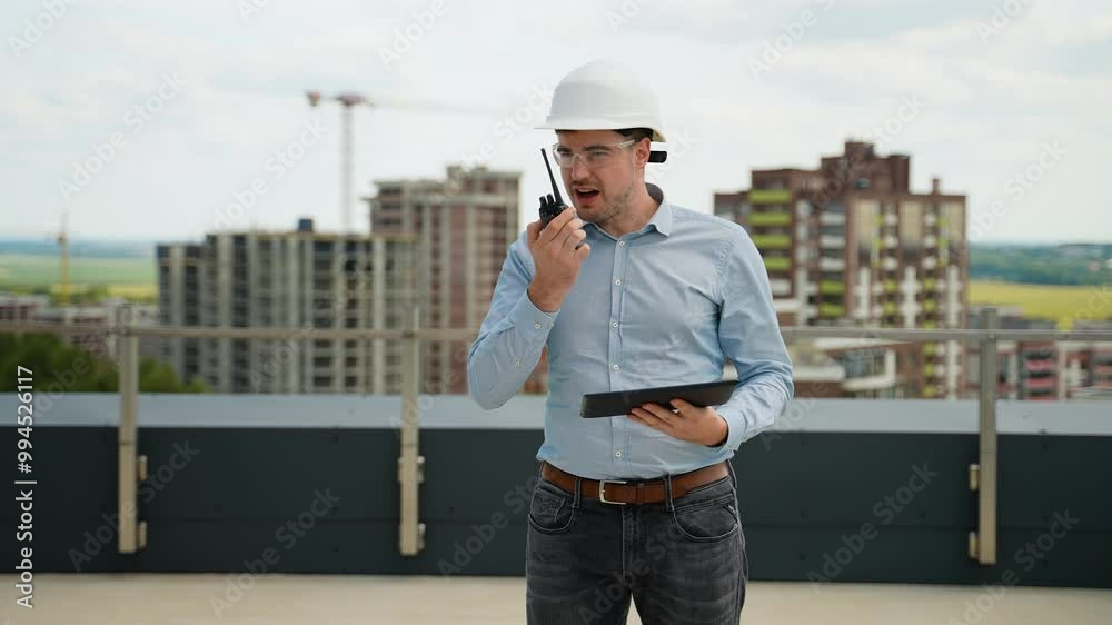 Construction engineer using walkie-talkie and tablet on rooftop site Construction engineer using walkie-talkie and tablet on rooftop site