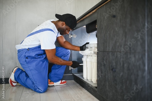 Technician installing reverse osmosis equipment under the sink