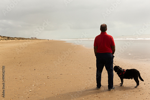 Hombre paseando por la playa con su perro labrador. photo