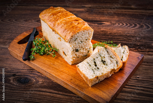 Traditional bayrisches Kasten Zupfbrot mit Knoblauch Kräuter Butter serviert als Nahaufnahme auf einem Holz Schneidebrett  photo