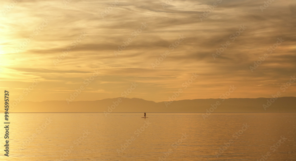 Peaceful sea scene with lone paddleboarder at sunset