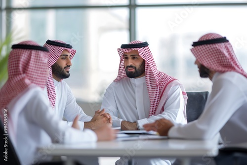 Saudi worker wearing full buttoned white thobe and red shemagh are meeting together in the meeting room
