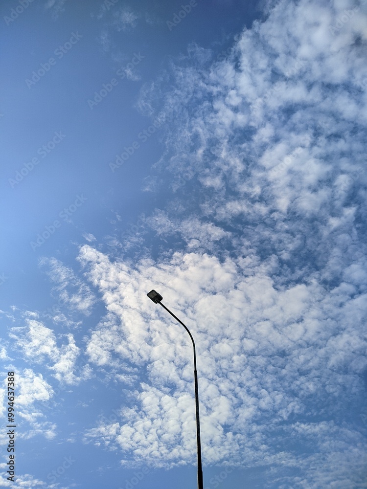 a street lighting pole against a cloudy blue sky