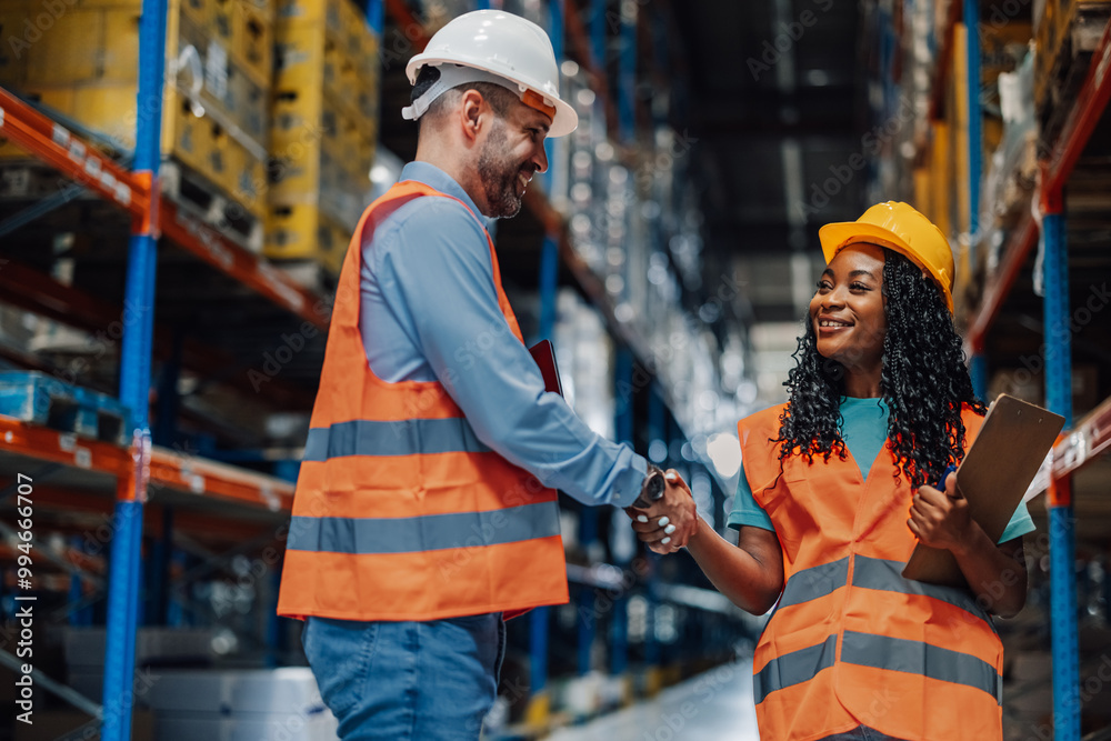 Handshake seals collaboration between two diverse warehouse workers. Handshake seals collaboration between two diverse warehouse workers.
