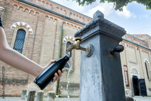 Fototapeta Naklejka Na Ścianę i Meble -  A person fills a thermos bottle at a nasone, a free public water fountain in Italy