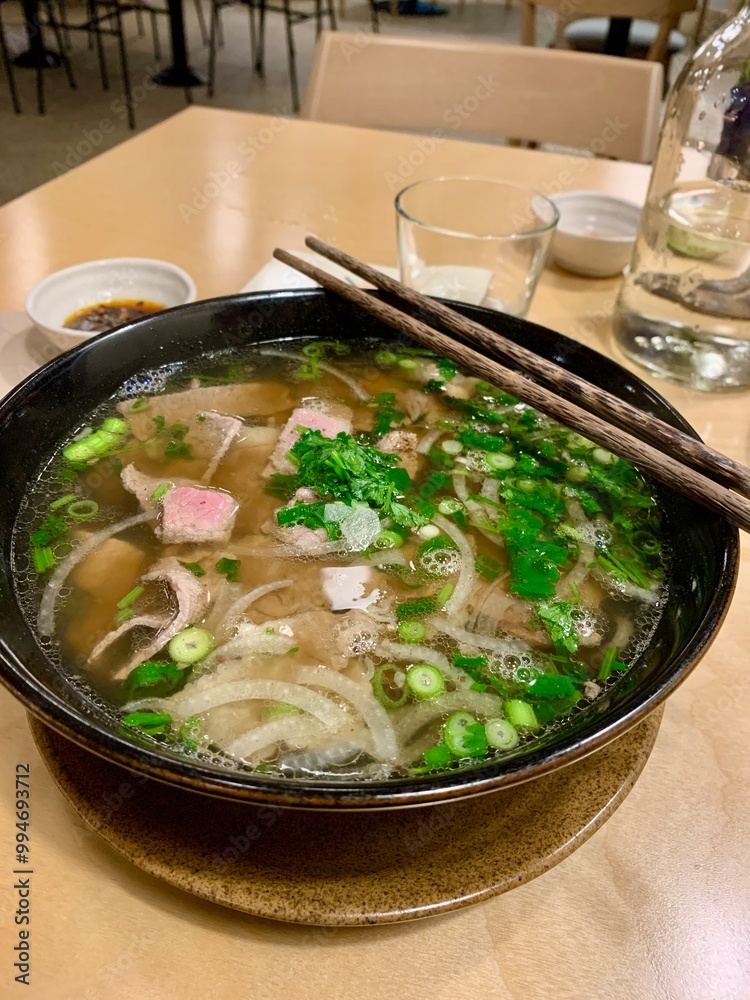 Freshly prepared Pho Vietnamese Noodle Soup, with green onions and cilantro, in a bowl