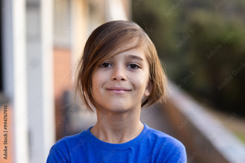 Smiling boy in blue shirt standing outside school building with arms crossed Smiling boy in blue shirt standing outside school building with arms crossed