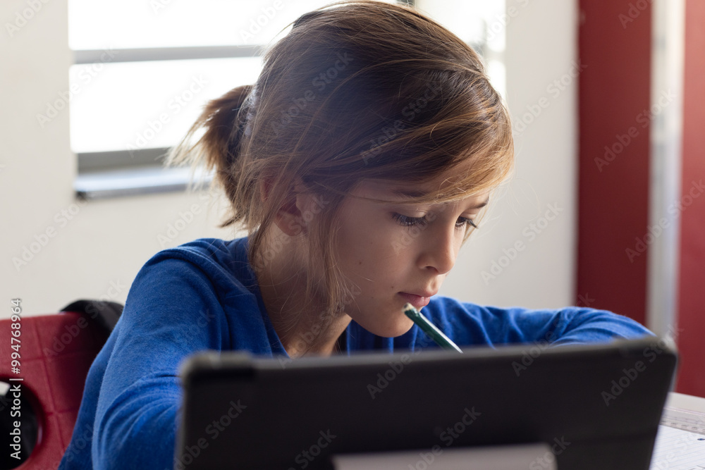 In school, boy studying with tablet and pencil, concentrating on work