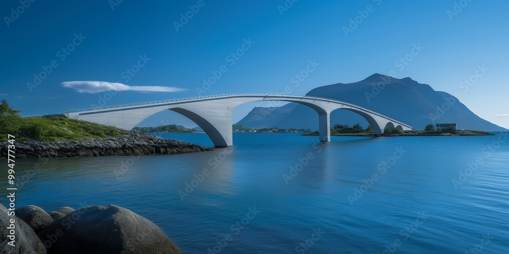 Naklejka premium A stunning white arch bridge stretches across the crystal-clear blue waters, with mountains in the background.