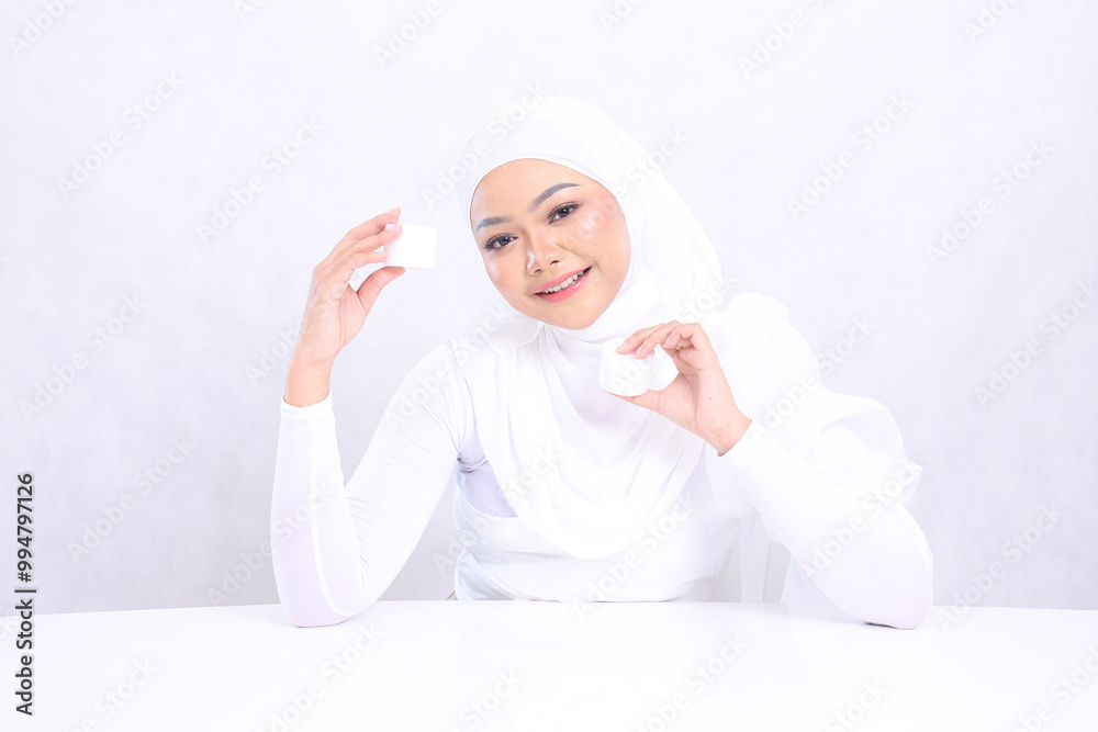 Charm Beautiful young veil woman indonesia smiling cheerfully to the camera both hands holding cosmetic cream satisfied in her skin care routine on white background. Perfect skin, Natural makeup Charm Beautiful young veil woman indonesia smiling cheerfully to the camera both hands holding cosmetic cream satisfied in her skin care routine on white background. Perfect skin, Natural makeup
