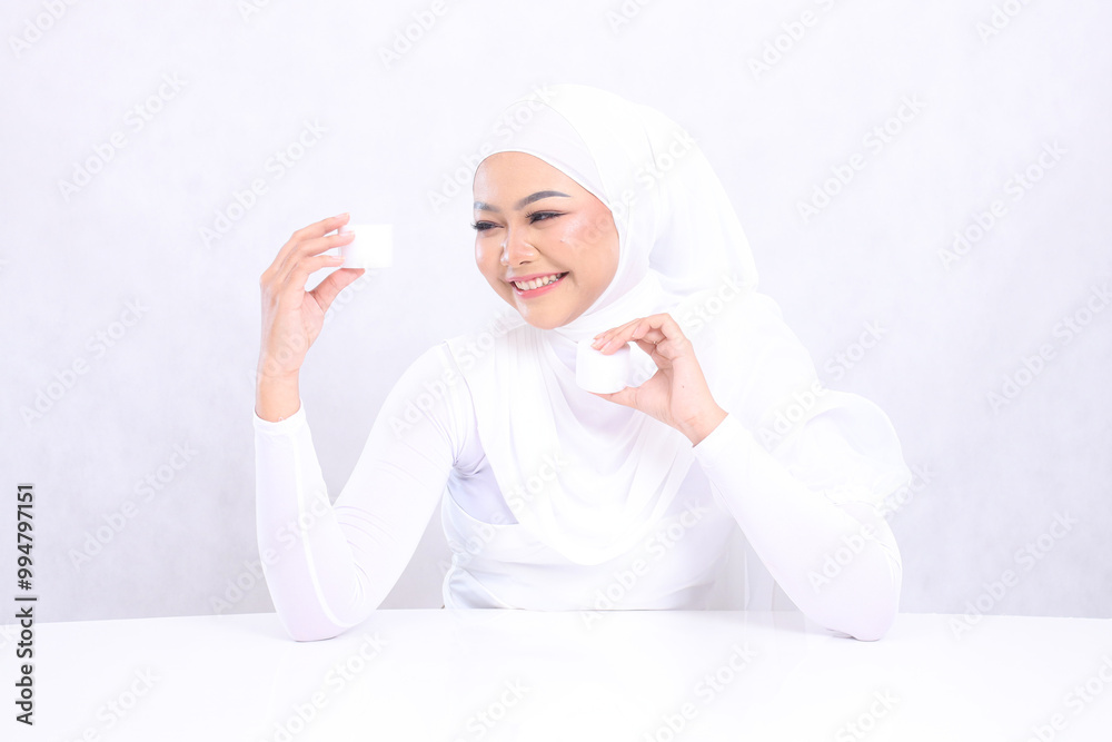Beauty Beautiful young hijab girl asia laughing candid right both hands holding cosmetic cream satisfied in her facial care routine on white background. Facial treatment, Natural makeup Beauty Beautiful young hijab girl asia laughing candid right both hands holding cosmetic cream satisfied in her facial care routine on white background. Facial treatment, Natural makeup