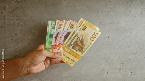Hand holding norwegian krone banknotes against concrete background showing currency from norway