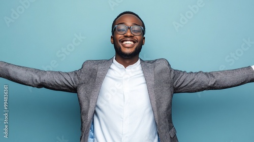 Joyful professional celebrating success with arms wide open against turquoise background, exuding confidence and achievement in modern workplace setting. photo