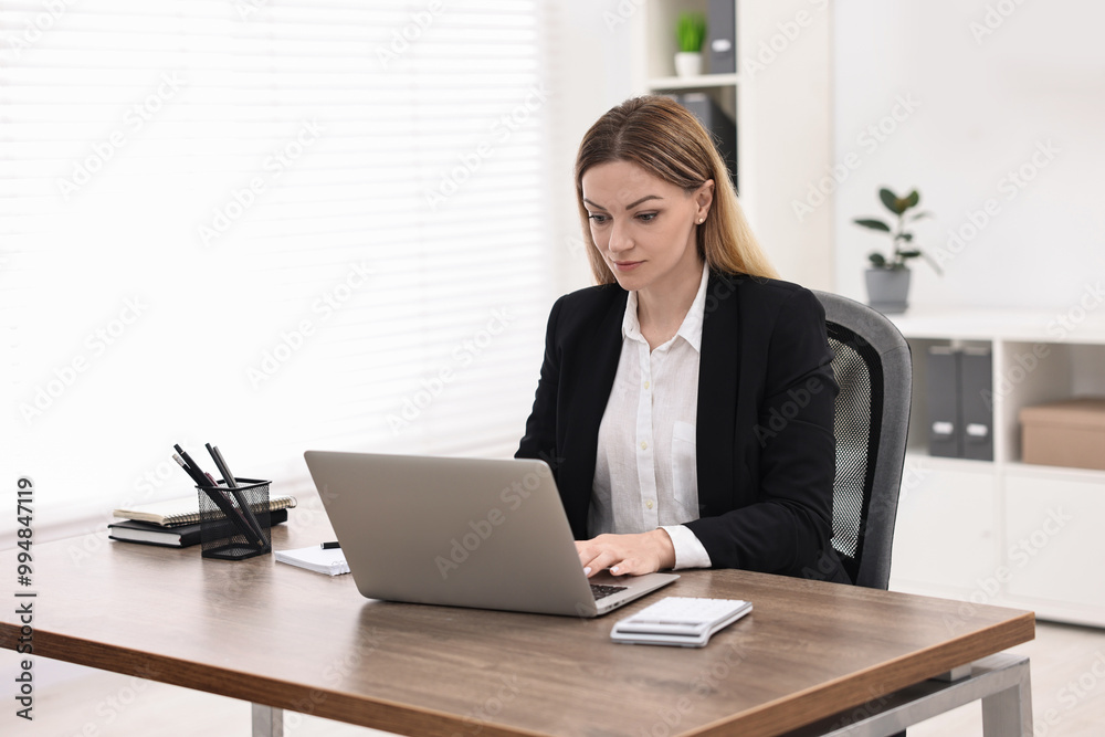 Banker using laptop at wooden table in office Banker using laptop at wooden table in office