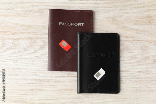 Passports and SIM cards on wooden table, flat lay