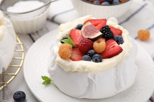 Pavlova cake (meringue dessert) with whipped cream, fresh berries, fig and mint on table, closeup