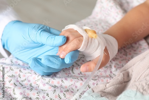 Doctor and child with intravenous drip at hospital, closeup