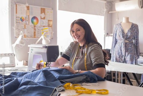 Woman plus size fashion designer uses a sewing machine in her studio.  photo