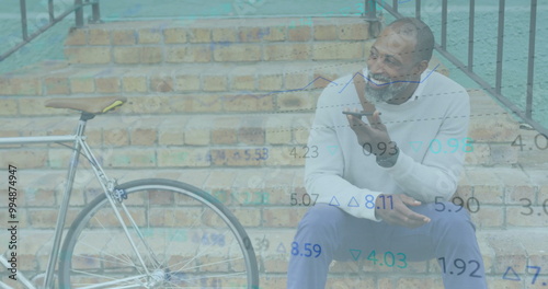 Image of financial data processing over african american man using smartphone in city