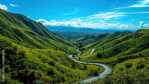 A lush green valley nested in the rugged terrain of the Dominican Republic, featuring a winding road, rolling hills, and distant mountain ranges under a radiant blue sky. photo