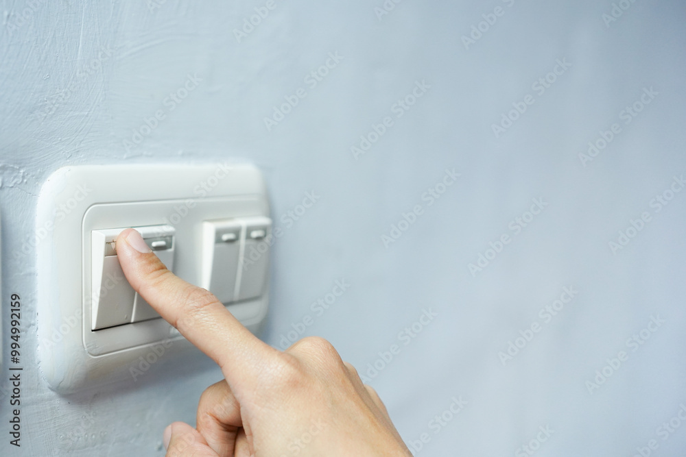 Woman pressing a light switch, energy saving concept