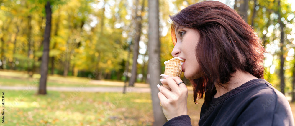 Fototapeta premium Carefree portrait of a smiling girl relishing a delicious ice cream cone while outdoors.