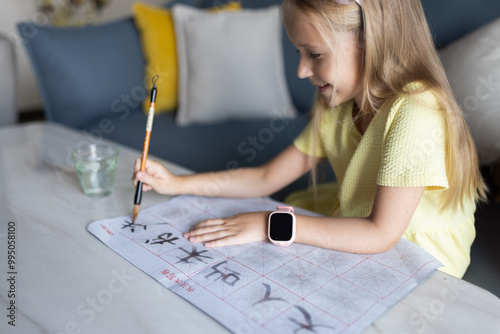 Cute little caucasian girl seven years old with blonde hair writing Chinese characters at home photo