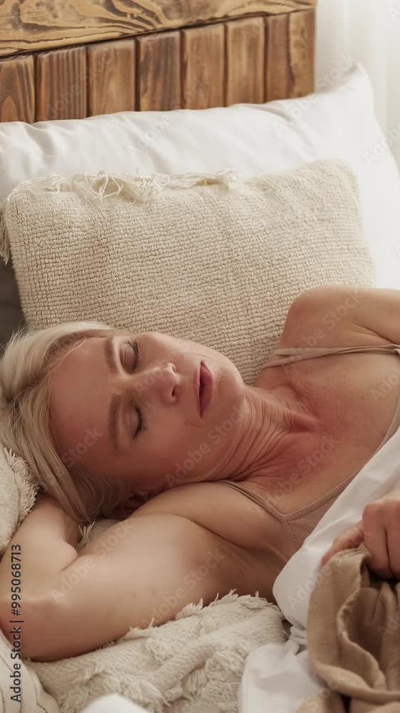 Vertical video. Bad sleep. Uncomfortable bed. Annoyed displeased woman tossing and turning on mattress and pillows covered with blanket at home free space. Vertical video. Bad sleep. Uncomfortable bed. Annoyed displeased woman tossing and turning on mattress and pillows covered with blanket at home free space.
