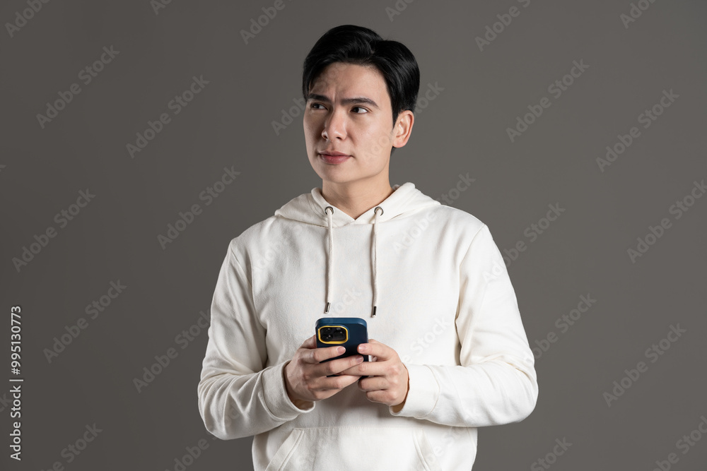 Portrait of Asian man wearing hoodie and posing on gray background. Portrait of Asian man wearing hoodie and posing on gray background.