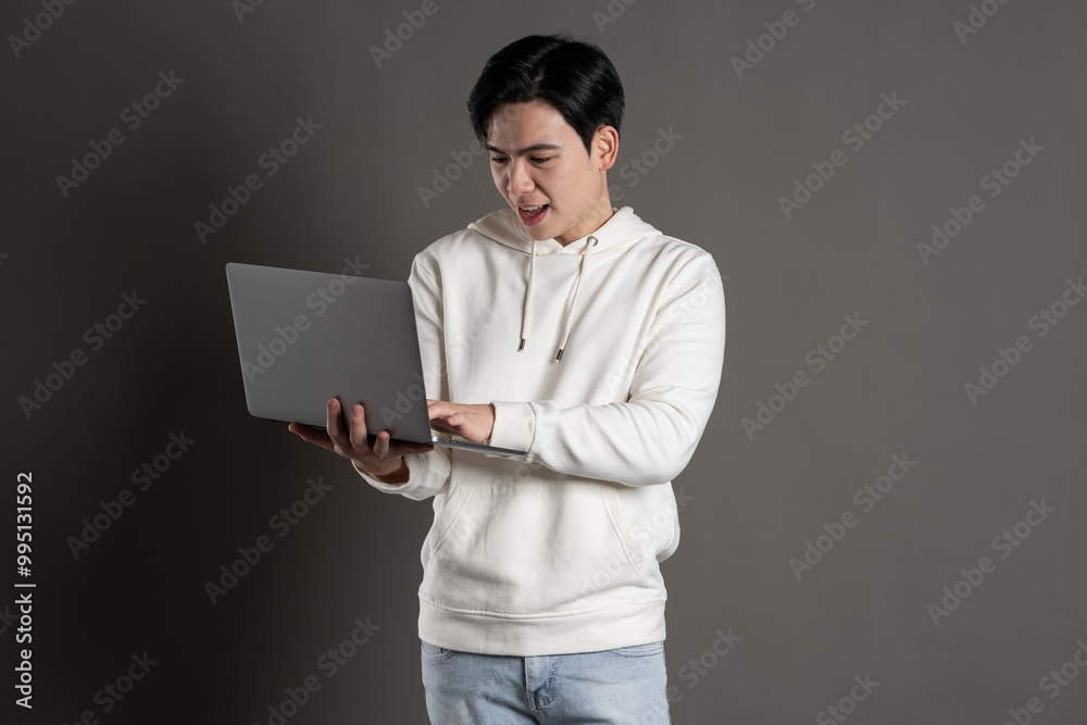 Portrait of Asian man wearing hoodie and posing on gray background. Portrait of Asian man wearing hoodie and posing on gray background.
