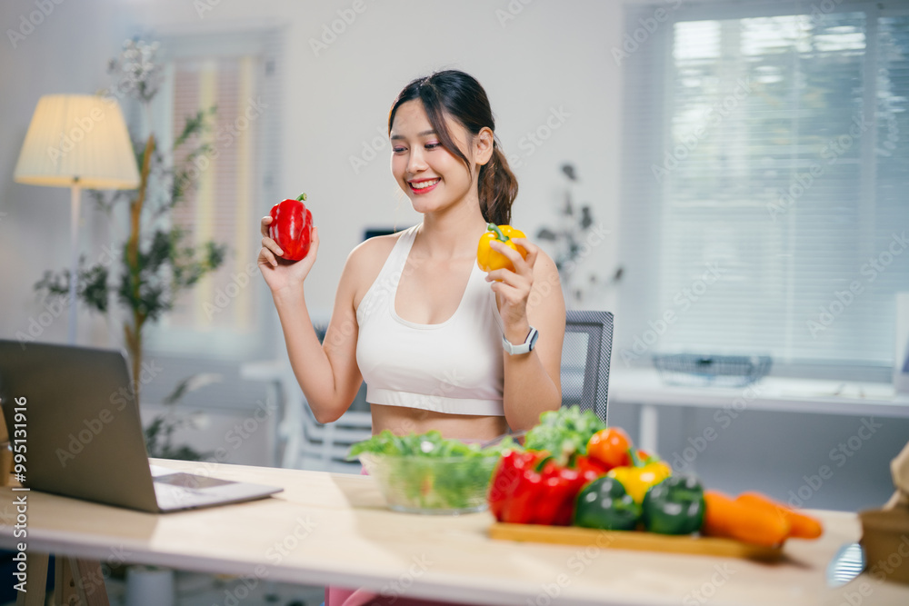 Asian nutritionist compares bell peppers while working on her laptop, offering online health consultations and promoting a healthy diet and lifestyle Asian nutritionist compares bell peppers while working on her laptop, offering online health consultations and promoting a healthy diet and lifestyle