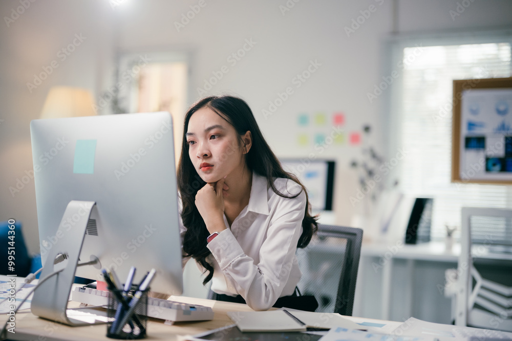Focused young businesswoman works at a modern office desk, analyzing data on her laptop with determination and expertise Focused young businesswoman works at a modern office desk, analyzing data on her laptop with determination and expertise