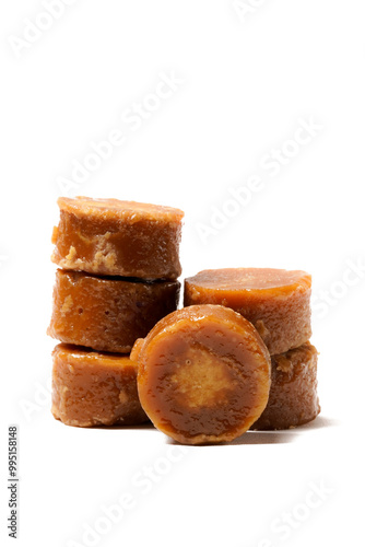 A neatly arranged of traditional brown sugar (gula jawa) cylindrical blocks isolated on a clean white background. The rich, caramel color contrasts beautifully with the crisp, minimalist backdrop
