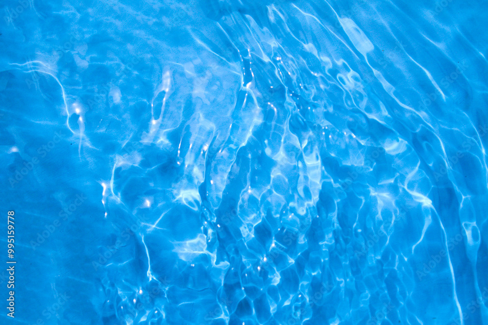 Blue water with ripples on the surface. Defocus blurred transparent blue colored clear calm water surface texture with splashes and bubbles. Water waves with shining pattern texture pool Blue water with ripples on the surface. Defocus blurred transparent blue colored clear calm water surface texture with splashes and bubbles. Water waves with shining pattern texture pool