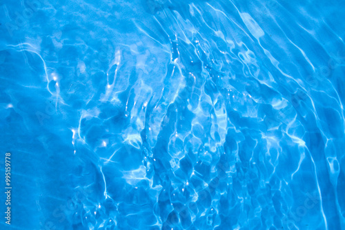 Blue water with ripples on the surface. Defocus blurred transparent blue colored clear calm water surface texture with splashes and bubbles. Water waves with shining pattern texture pool photo