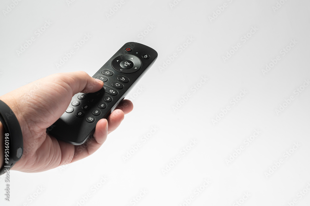 Human hand using TV remote control over white background Human hand using TV remote control over white background