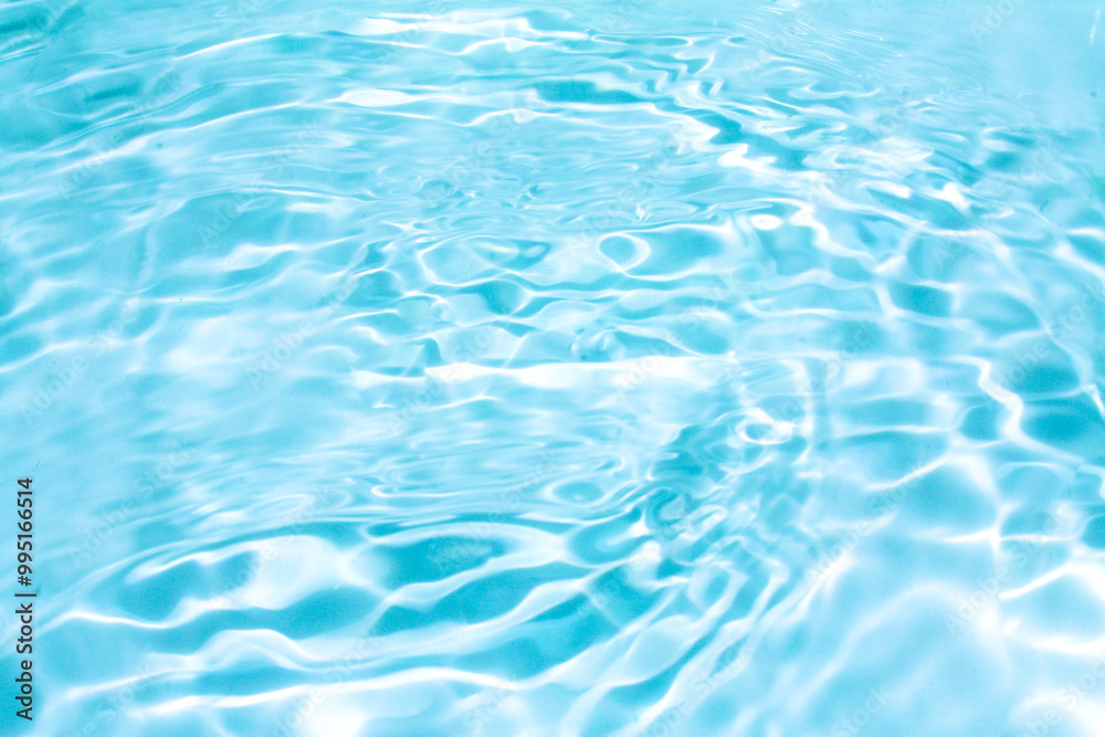 Blue water with ripples on the surface. Defocus blurred transparent blue colored clear calm water surface texture with splashes and bubbles. Water waves with shining pattern texture background.