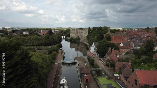 Aerial Drone footage starting behind a River Boat in Newark Town Lock that moving up and forward over to Newark Castle and Gardens and panning down over the Castle and Gardens. photo