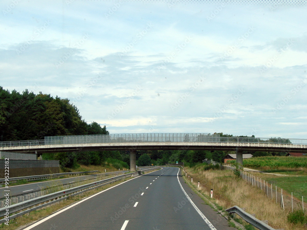 Panorama of the highway from the car window in front of the railway bridge on the background of a cloudy sky. Panorama of the highway from the car window in front of the railway bridge on the background of a cloudy sky.