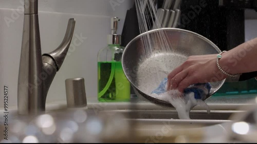  woman washing. stainless steel pan in kitchen sink slow motion closeup