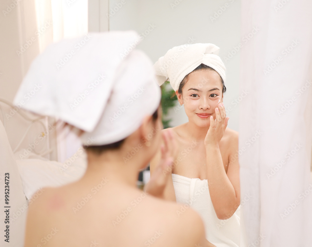 Skin care beauty on face, smiling beautiful asian woman in bathrobe looking in mirror and using serum cream to nourish skin in daily life. Skin care beauty on face, smiling beautiful asian woman in bathrobe looking in mirror and using serum cream to nourish skin in daily life.