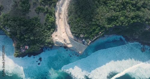 Top Down Drone Video of Turquoise Waves Crashing Against Environmental Destruction of the Limestone Cliffs near Pura Luhur Uluwatu Temple, Bali Indonesia with Massive Earth Clearing photo